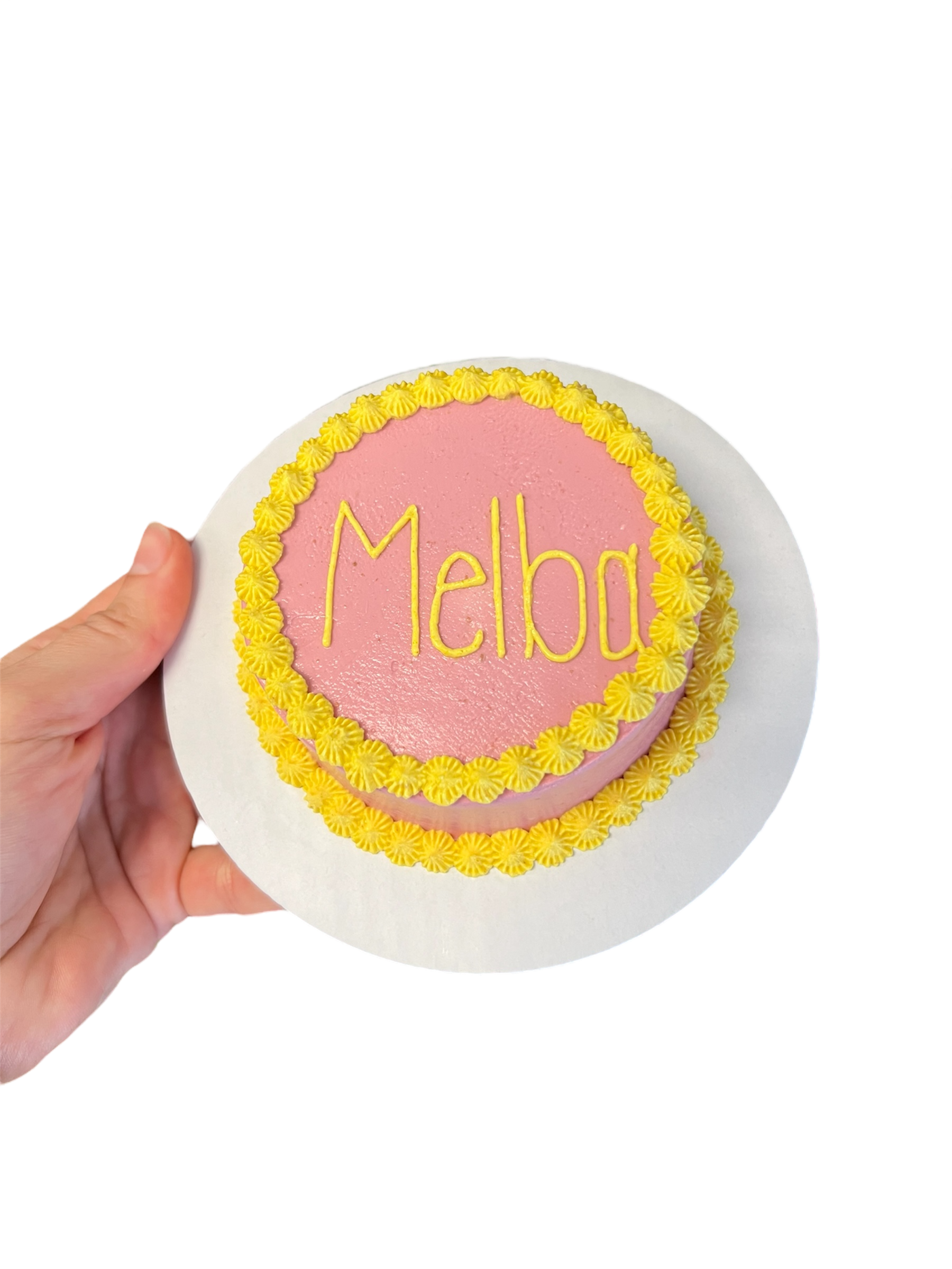 Circle dog birthday cake decorated with pink frosting and yellow floral edges for celebrating pets