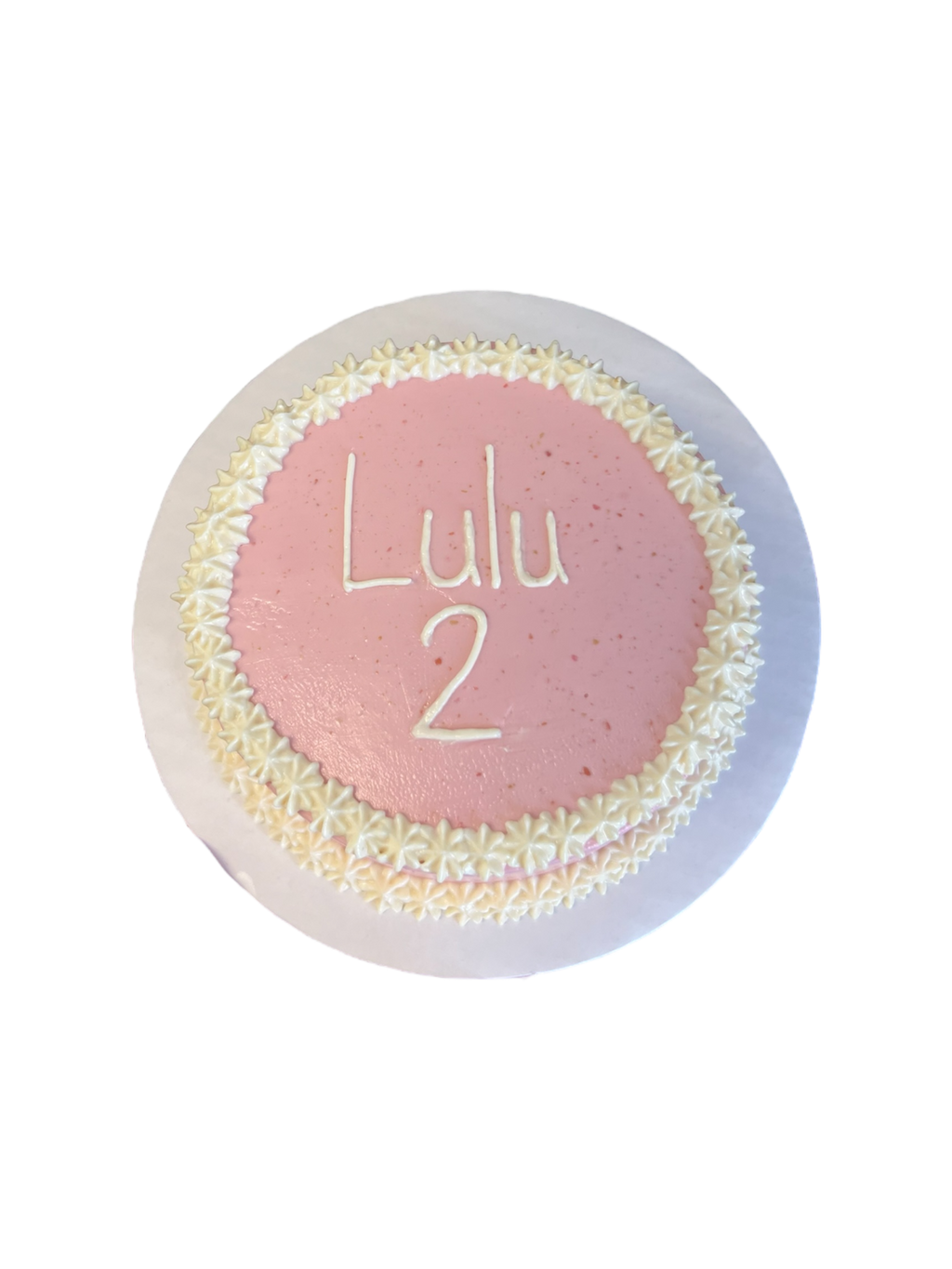 Circle dog birthday cake decorated with pink icing and white flower accents for pet celebrations