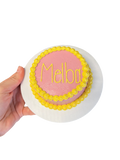 Circle dog birthday cake decorated with pink frosting and yellow floral edges for celebrating pets