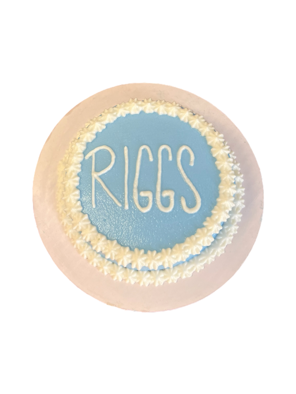 Circle dog birthday cake customized with blue frosting and the name Riggs on top