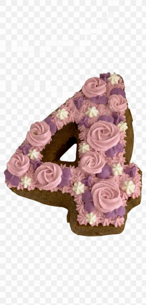 Organic dog birthday cake shaped like the number four decorated with pink and purple frosting flowers
